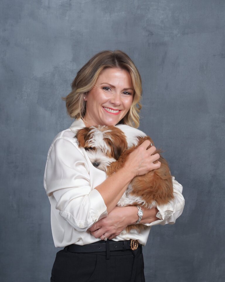 Woman holding a small puppy in a studio portrait