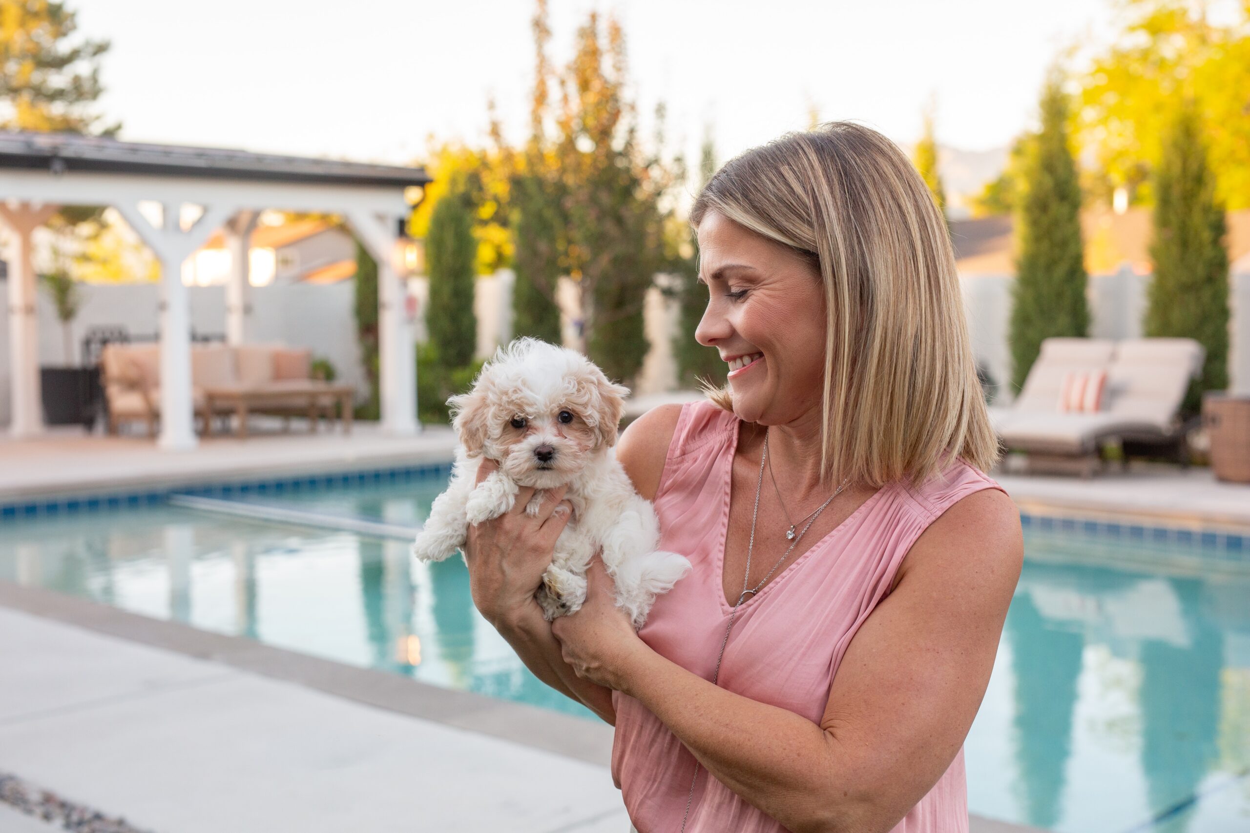 Sage Puppies breeder holding a small cream puppy beside a pool in South Jordan Utah