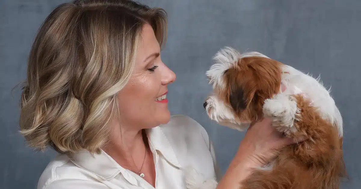 Sage Puppies breeder gently holding a red and white Havapoo puppy