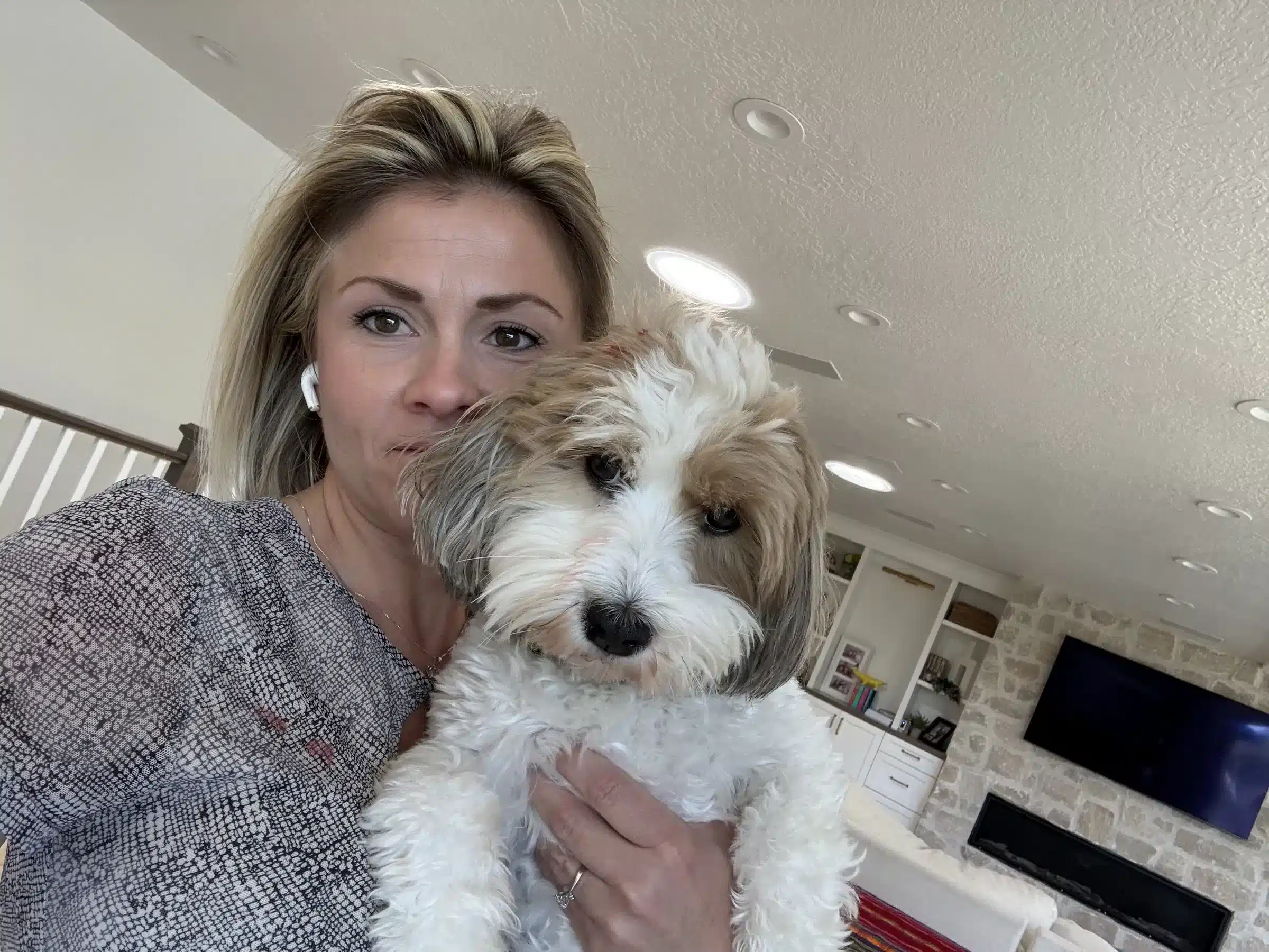 Woman With Small Dog | New York Family-Fit Guide Woman holding a fluffy white-and-tan small dog indoors, shown in a guide for New York families